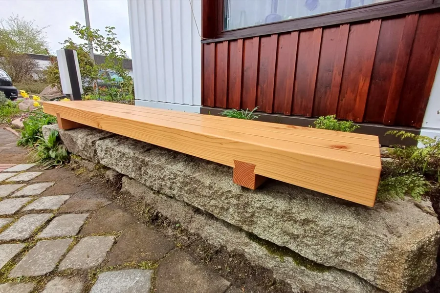 Maßgefertigte Sitzbank aus Massivholz an einer Mauer